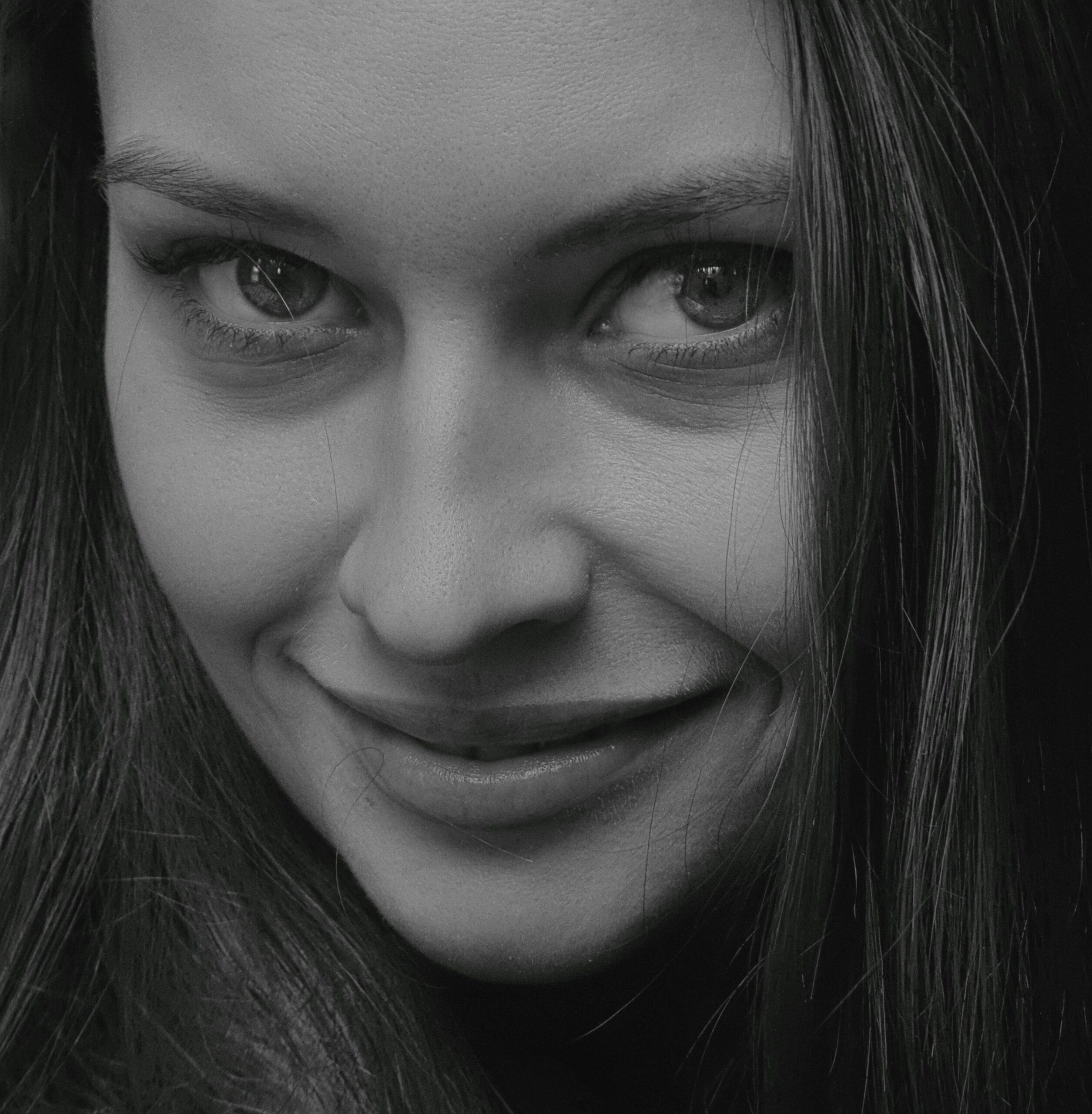 Close-up black and white portrait of a smiling woman with expressive eyes.